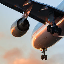 Low angle view of airplane flying against sky during sunset