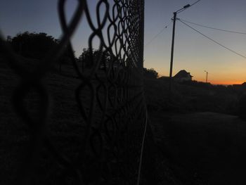 Silhouette of barbed wire against sky during sunset