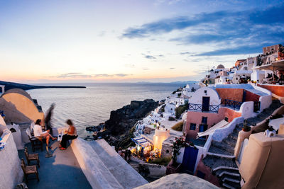 Buildings by aegean sea against sky during sunset