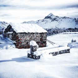 House by alps against sky during winter