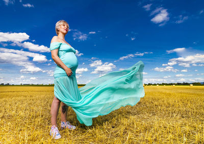 Woman standing on field against blue sky