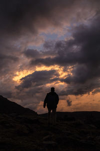 Rear view of silhouette man standing against sky during sunset