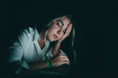 Portrait of young woman against black background