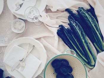 High angle view of raw food on a setting table with plates and drinking glass