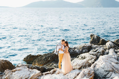 Couple standing on rock at beach