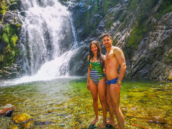 Full length of woman and man with waterfall in water