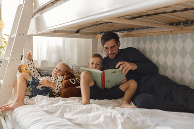 Father with sons reading book on bed