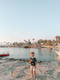 Boy standing on shore against sky