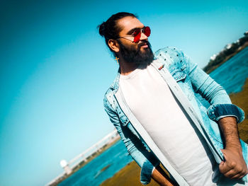 Low angle view of young man standing against blue sky