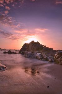 Scenic view of beach against sky at sunset