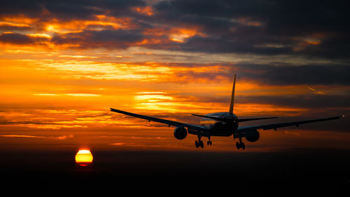 Airplane flying in sky during sunset