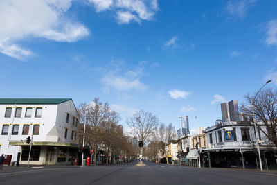 Road by buildings in city against sky