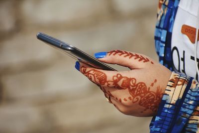 Close-up of woman hand holding mobile phone outdoors