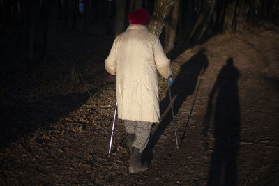 Rear view of people walking on field in forest