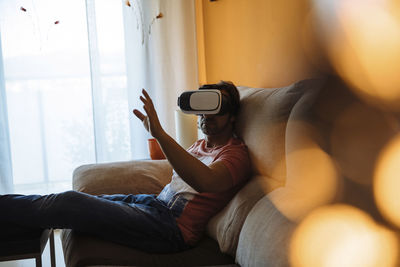 Man gesturing while using virtual reality on sofa at home