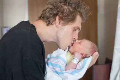 Close-up of man kissing newborn daughter in hospital