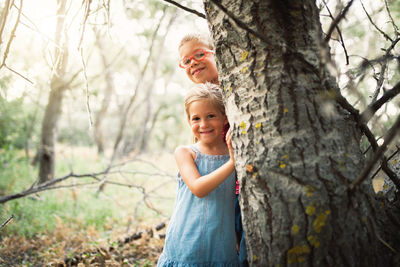 Smiling boy and girl by tree trunk