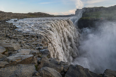 Scenic view of waterfall against sky