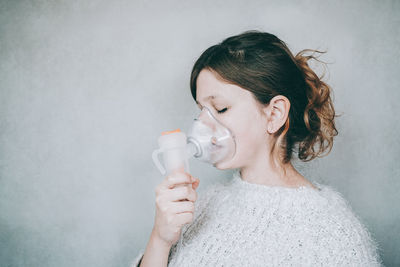 Portrait of woman drinking glass against wall