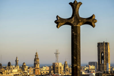 Cross in city against sky