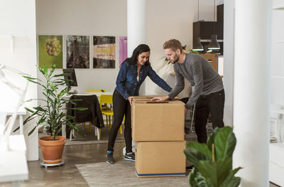 Multi-ethnic business colleagues moving cardboard boxes in creative office