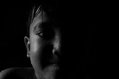 Close-up portrait of boy against black background