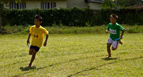 Boys running on grassy field during competition