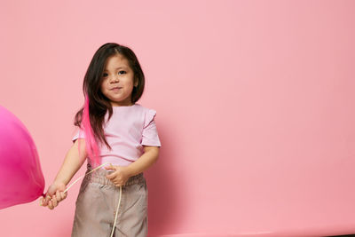 Portrait of young woman standing against wall