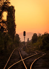 Railroad tracks against orange sky