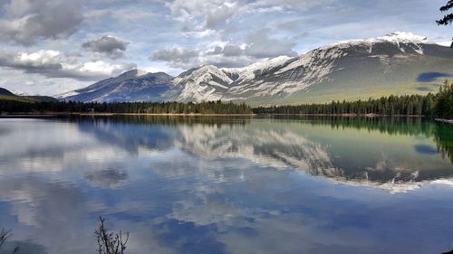 Scenic view of calm lake by mountains against cloudy sky