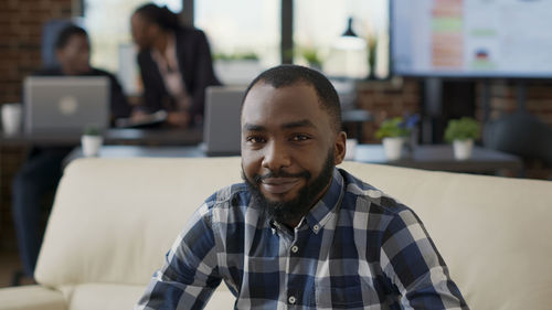 Portrait of young businessman sitting on sofa in office