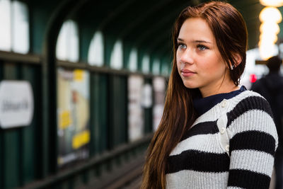 Close-up of young woman standing at railroad station