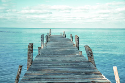 Wooden pier on sea against sky