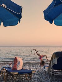 Low section of people standing on beach against clear sky