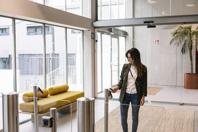 Mid adult woman showing id card at reader while entering office