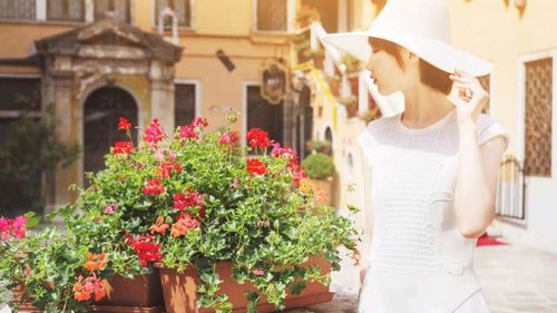 Woman wearing hat while standing by flowering plant