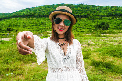 Portrait of smiling woman wearing sunglasses while gesturing on land