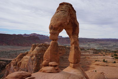 Rock formation on landscape against cloudy sky