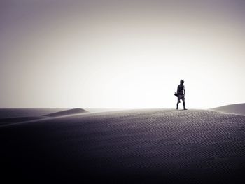 Person standing on landscape against clear sky