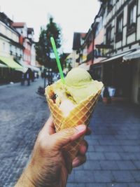 Cropped hand holding ice cream cone in city