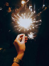 Hand holding firework display at night