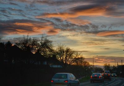Car on road against cloudy sky at sunset