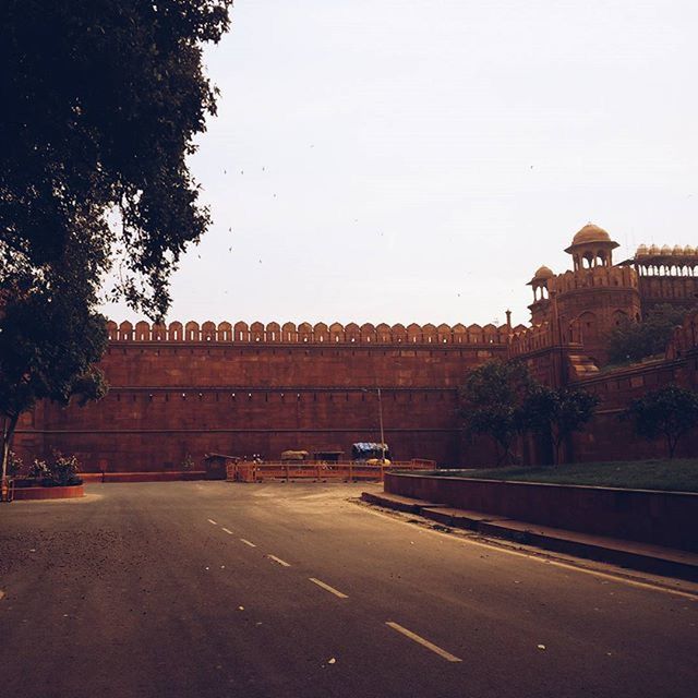 architecture, built structure, building exterior, clear sky, transportation, road, the way forward, street, copy space, road marking, sky, city, tree, diminishing perspective, outdoors, vanishing point, empty, no people, car, building