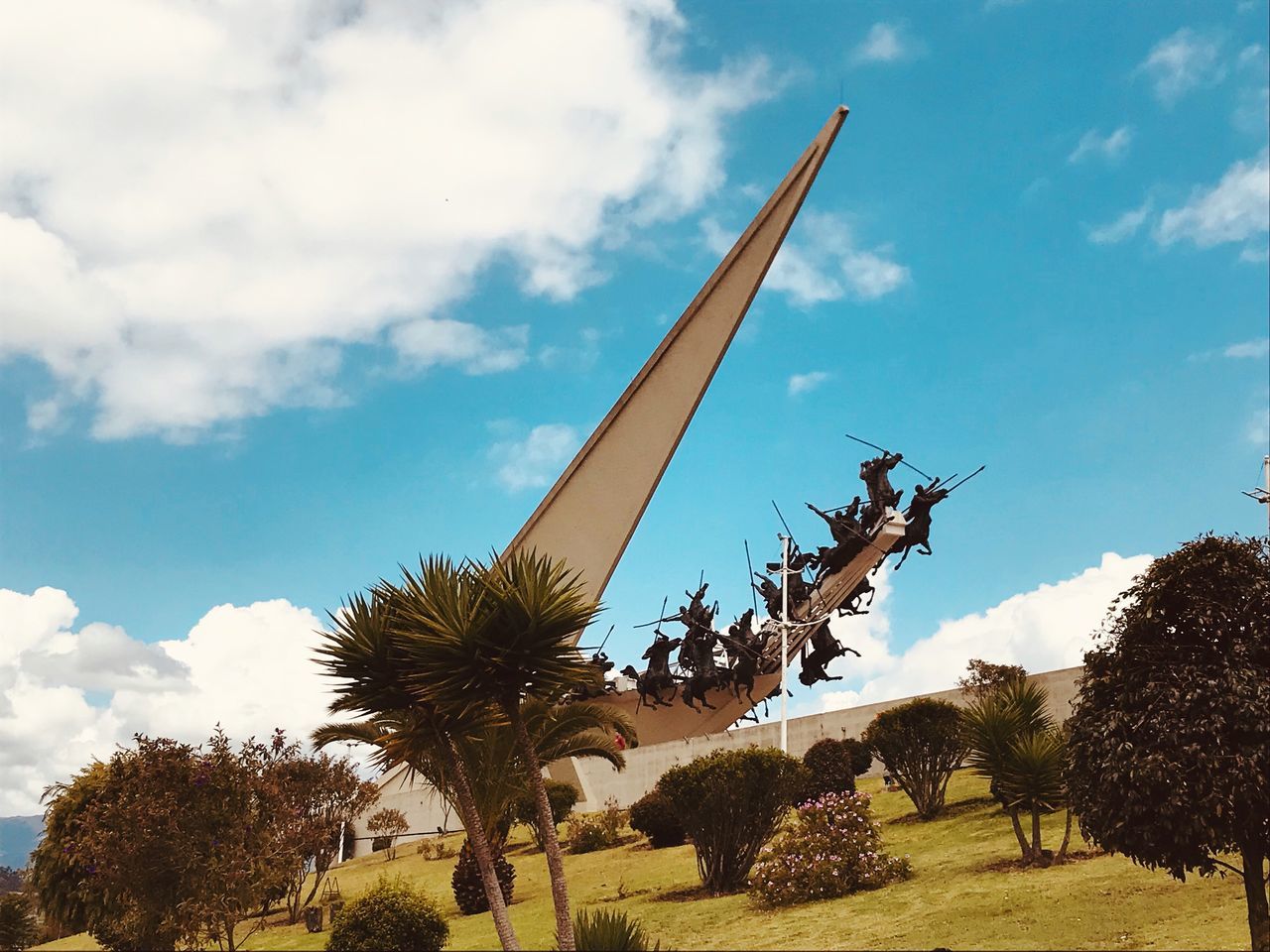 LOW ANGLE VIEW OF STATUE BY PALM TREES AGAINST SKY IN PARK