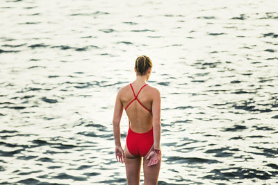 Rear view of teenager standing against river