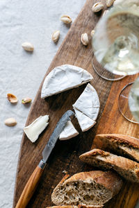 Two glasses of white wine and a wooden board with appetizers on the table.