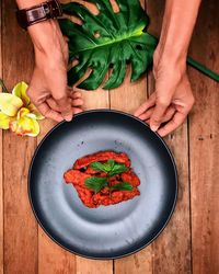 Cropped hands of woman holding plate with food on table