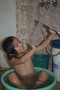 Midsection of woman with arms raised in bathroom