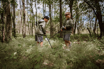 Young boys going metal detecting in a field.