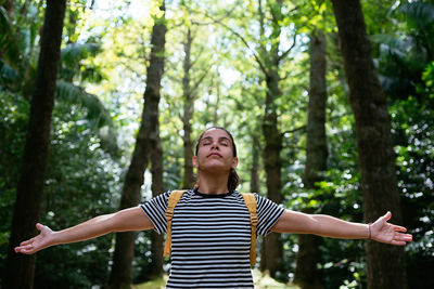 Full length of woman standing by tree in forest